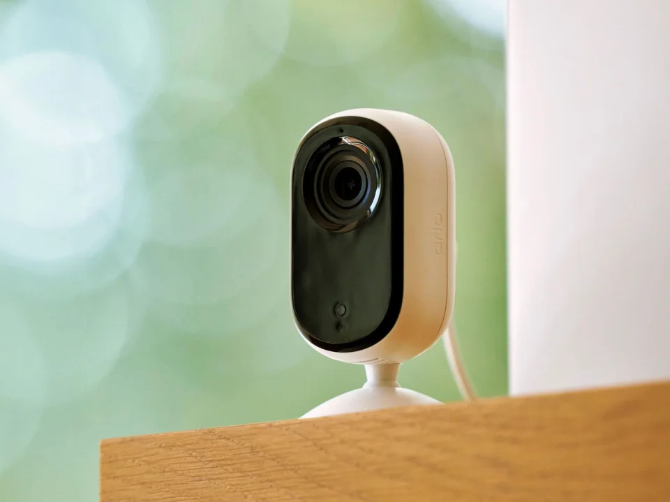 Arlo Essential Indoor Camera 2nd Gen close-up lifestyle shot on a wooden shelf
