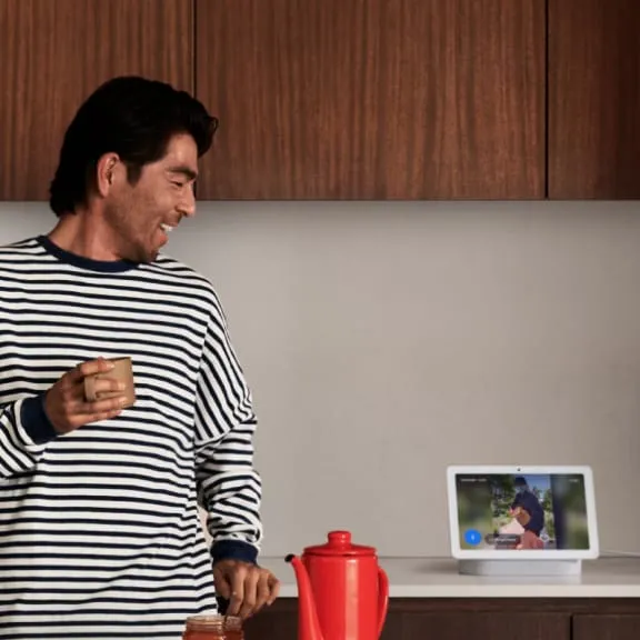 Person viewing a Nest Cam person-detection event on a Nest Hub in a kitchen