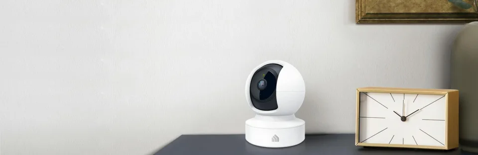 White Kasa EC70 pan-tilt camera on a table next to a clock