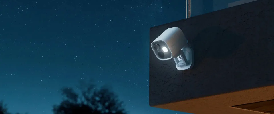 White Aqara Camera Hub G5 Pro wall-mounted outdoors at night with its spotlight on