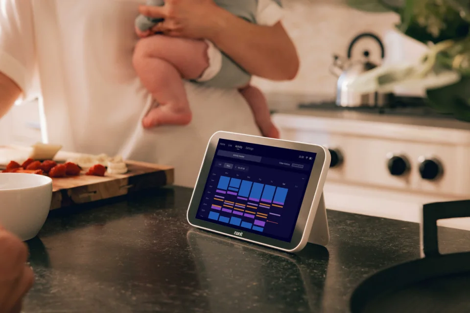 Nanit Pro Camera and Floor Stand set up beside a crib in a bright nursery