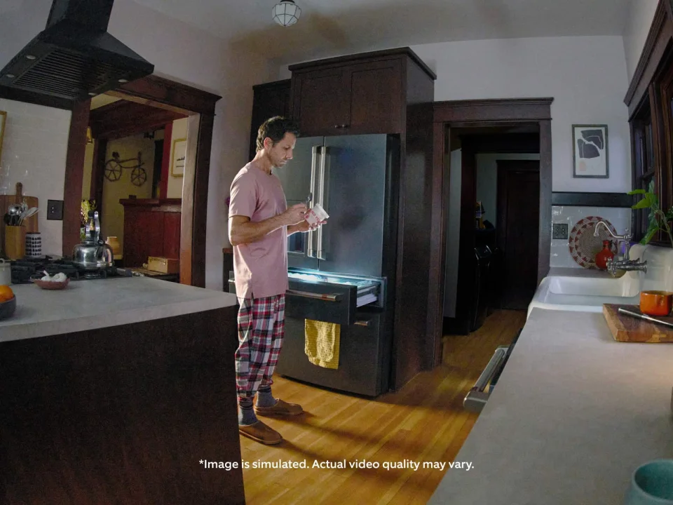 Simulated Ring Indoor Cam Plus Low-Light Sight view of a kitchen at night with a person at an open refrigerator