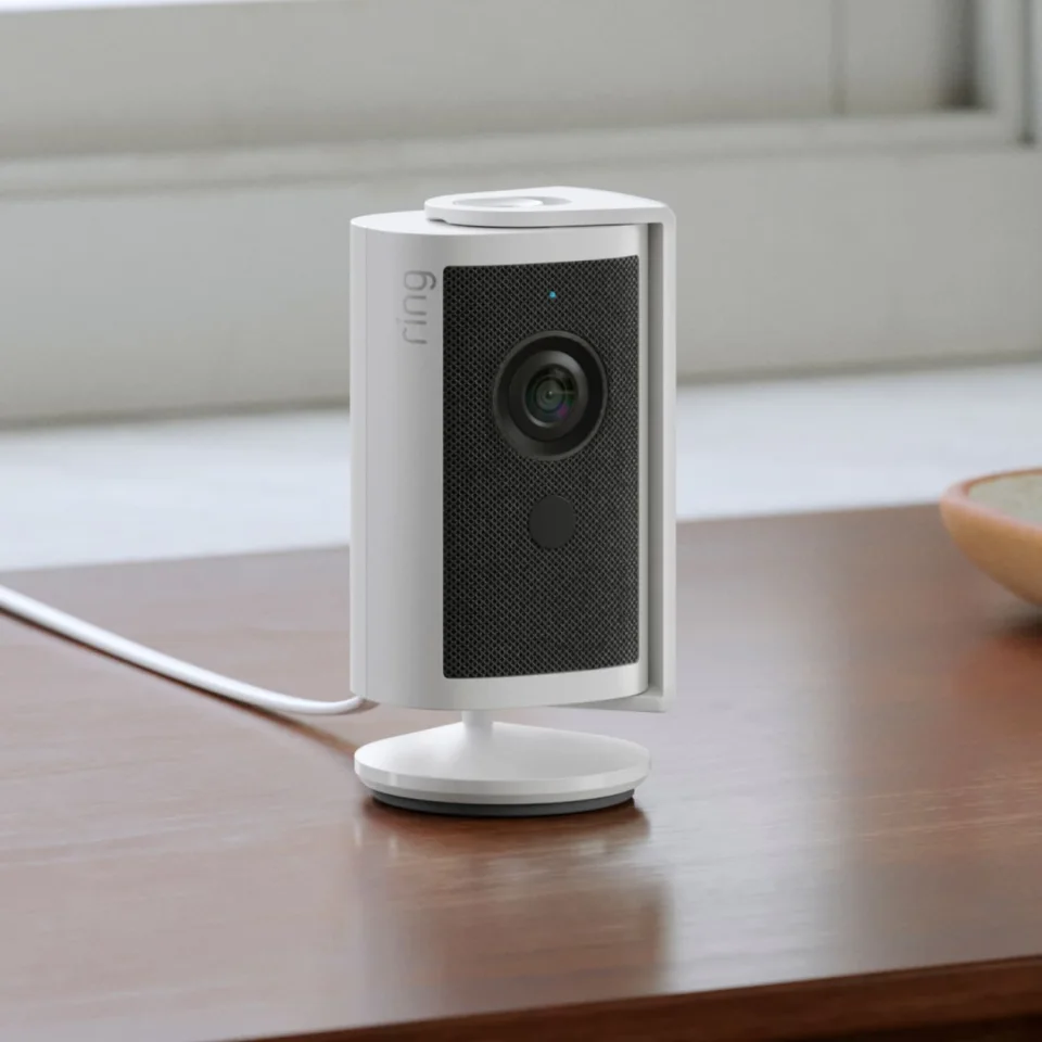 Ring Indoor Cam 4K in white on a wooden table, fixed position with detachable lens cover on top