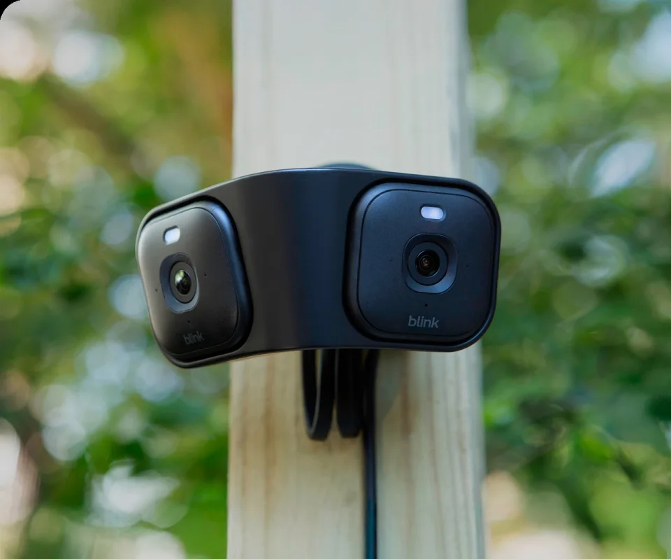 Two black Blink Mini 2K+ cameras mounted on a Blink Arc mount on an outdoor post