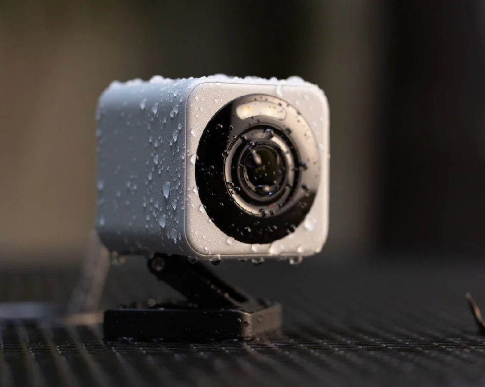 Wyze Cam v4 covered in water droplets outdoors, showing its IP65 weather resistance