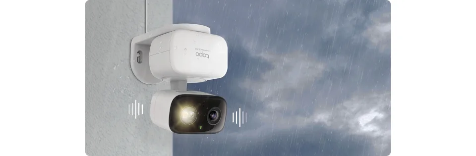 Tapo C216 wall-mounted outdoors in the rain with its spotlight on, Tapo branding and Crystal Clear 2K 3MP text visible