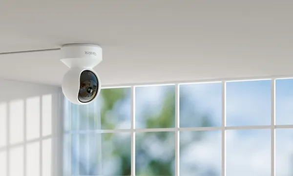 Reolink E1 pan-and-tilt camera mounted upside down on a ceiling in front of large windows
