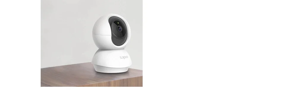 Tapo C210 white pan-and-tilt indoor camera with tapo logo on its bell-shaped base, standing on a wooden surface