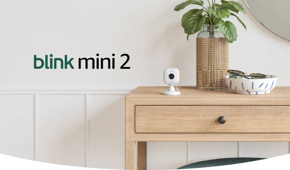 Blink Mini 2 compact indoor camera on a side table, official product photo