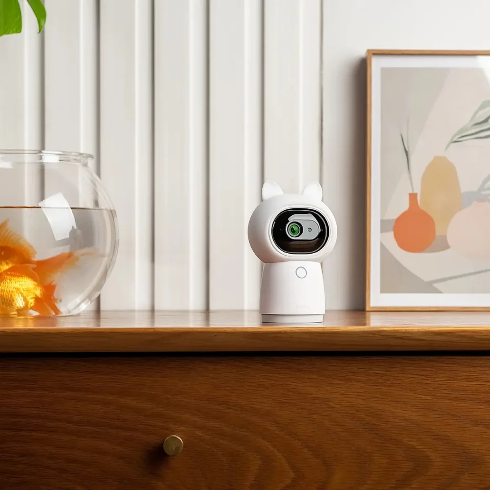 Aqara Camera Hub G3 with its cat-ear accessory on a wooden dresser in a living room